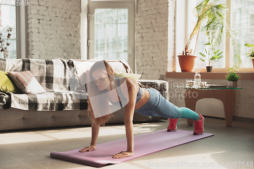 Image of Young woman teaching at home online courses of fitness, aerobic, sporty lifestyle while being quarantine