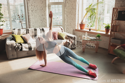 Image of Young woman teaching at home online courses of fitness, aerobic, sporty lifestyle while being quarantine