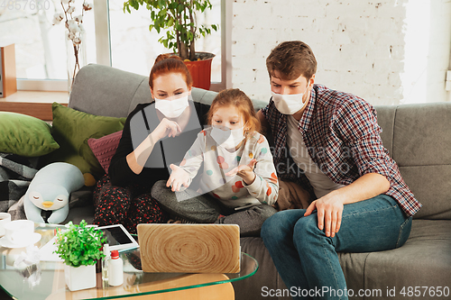Image of Caucasian family in protective masks and gloves isolated at home with coronavirus symptoms, treatment
