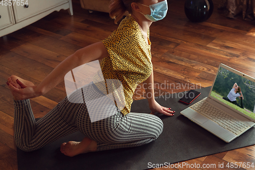 Image of Sporty young woman taking yoga lessons online and practice at home while being quarantine