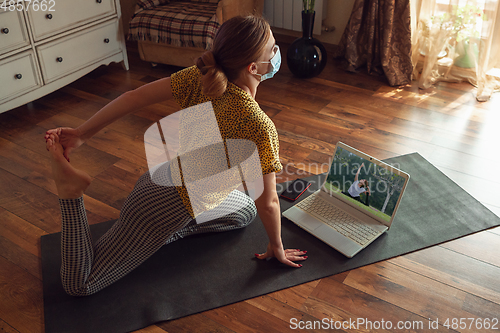 Image of Sporty young woman taking yoga lessons online and practice at home while being quarantine