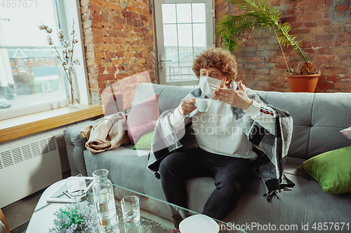 Image of Caucasian man in protective mask and glove isolated at home with coronavirus symptoms