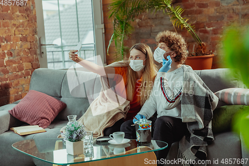 Image of Woman and man, couple in protective masks and gloves isolated at home with coronavirus symptoms