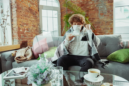 Image of Caucasian man in protective mask and glove isolated at home with coronavirus symptoms