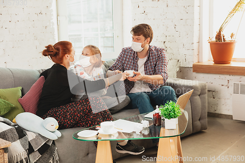 Image of Caucasian family in protective masks and gloves isolated at home with coronavirus symptoms, treatment