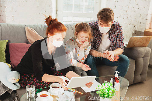 Image of Caucasian family in protective masks and gloves isolated at home with coronavirus symptoms, treatment