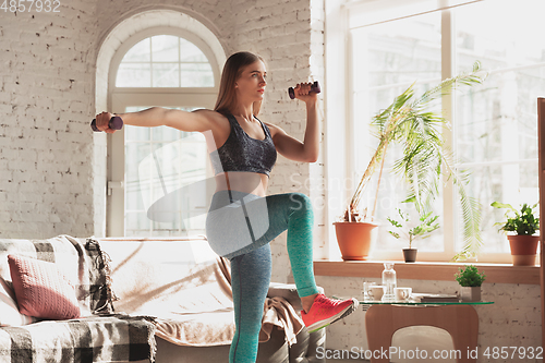 Image of Young woman teaching at home online courses of fitness, aerobic, sporty lifestyle while being quarantine