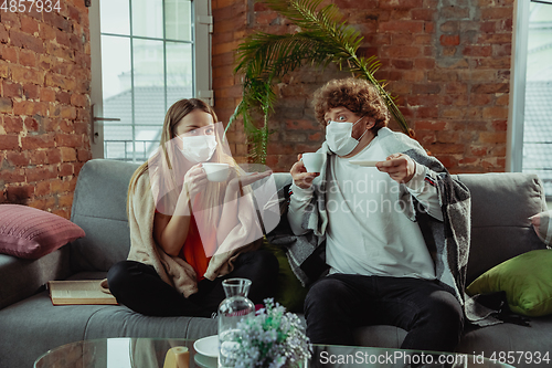 Image of Woman and man, couple in protective masks and gloves isolated at home with coronavirus symptoms