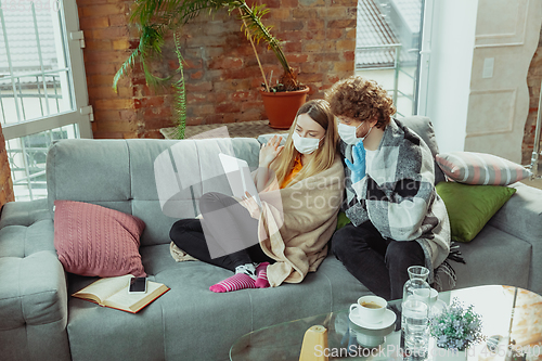 Image of Woman and man, couple in protective masks and gloves isolated at home with coronavirus symptoms