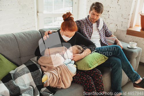 Image of Caucasian family in protective masks and gloves isolated at home with coronavirus symptoms, treatment