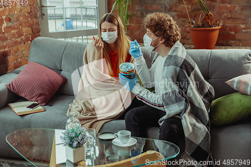 Image of Woman and man, couple in protective masks and gloves isolated at home with coronavirus symptoms