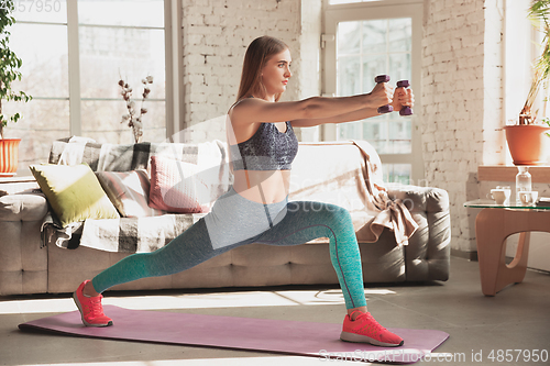 Image of Young woman teaching at home online courses of fitness, aerobic, sporty lifestyle while being quarantine