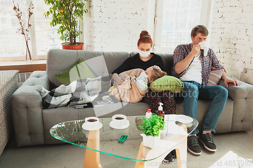 Image of Caucasian family in protective masks and gloves isolated at home with coronavirus symptoms, treatment