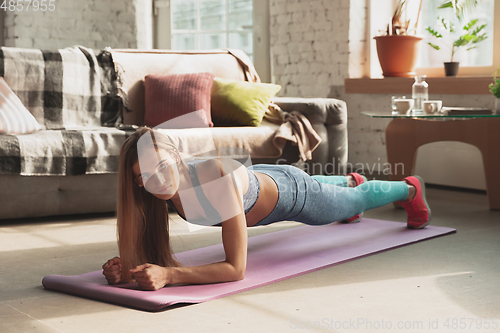 Image of Young woman teaching at home online courses of fitness, aerobic, sporty lifestyle while being quarantine