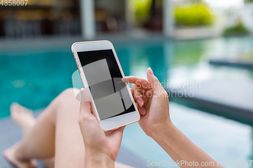 Image of Woman using her mobile phone and relaxing on swimming pool