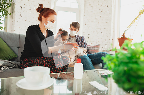 Image of Caucasian family in protective masks and gloves isolated at home with coronavirus symptoms, treatment