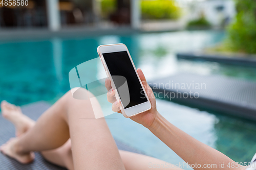 Image of Woman using cellphone and lying besides swimming pool