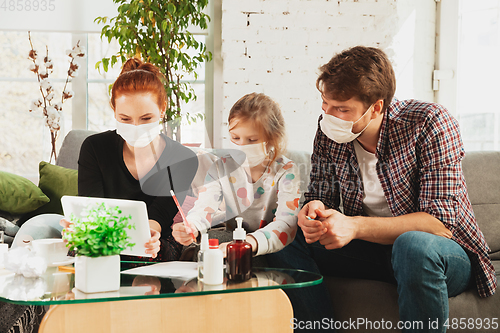 Image of Caucasian family in protective masks and gloves isolated at home with coronavirus symptoms, treatment