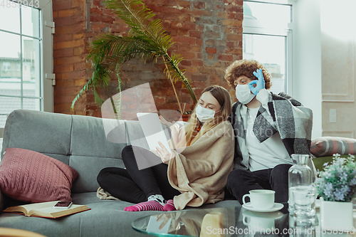 Image of Woman and man, couple in protective masks and gloves isolated at home with coronavirus symptoms