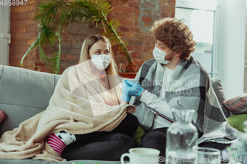Image of Woman and man, couple in protective masks and gloves isolated at home with coronavirus symptoms