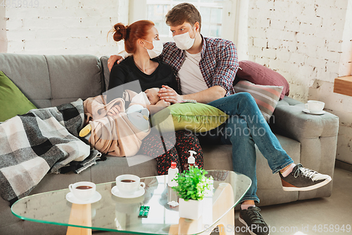 Image of Caucasian family in protective masks and gloves isolated at home with coronavirus symptoms, treatment