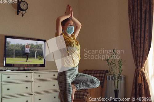 Image of Sporty young woman taking yoga lessons online and practice at home while being quarantine