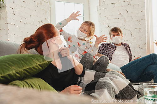 Image of Caucasian family in protective masks and gloves isolated at home with coronavirus symptoms, treatment