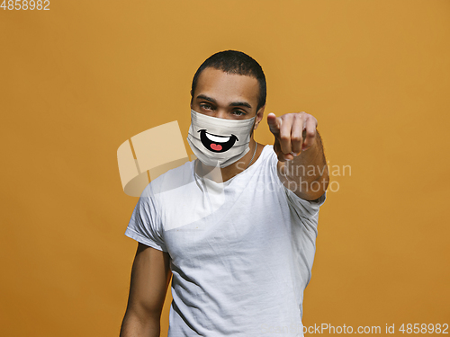 Image of Portrait of young african-american man with emotion on his protective face mask