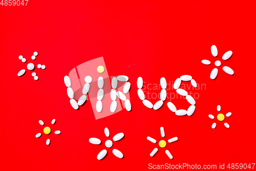 Image of Colored pills, tablets and capsules on a red background - history of treatment, prevention of pandemic