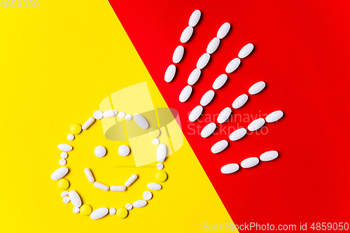 Image of Colored pills, tablets and capsules on a red and yellow background - history of treatment, prevention of pandemic