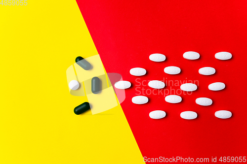 Image of Colored pills, tablets and capsules on a red and yellow background - history of treatment, prevention of pandemic