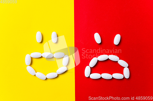 Image of Colored pills, tablets and capsules on a red and yellow background - history of treatment, prevention of pandemic