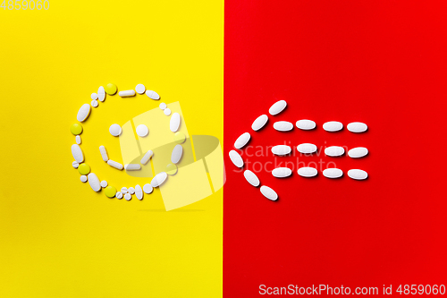 Image of Colored pills, tablets and capsules on a red and yellow background - history of treatment, prevention of pandemic