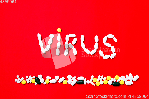 Image of Colored pills, tablets and capsules on a red background - history of treatment, prevention of pandemic