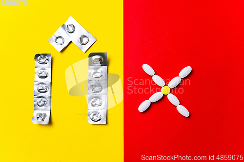 Image of Colored pills, tablets and capsules on a red and yellow background - history of treatment, prevention of pandemic