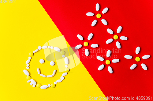 Image of Colored pills, tablets and capsules on a red and yellow background - history of treatment, prevention of pandemic