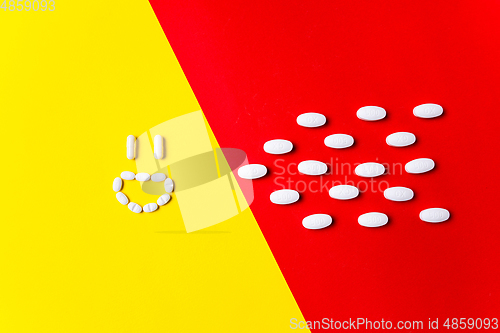 Image of Colored pills, tablets and capsules on a red and yellow background - history of treatment, prevention of pandemic