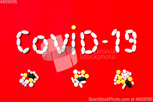 Image of Colored pills, tablets and capsules on a red background - history of treatment, prevention of pandemic