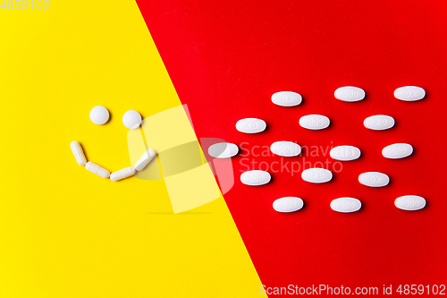 Image of Colored pills, tablets and capsules on a red and yellow background - history of treatment, prevention of pandemic