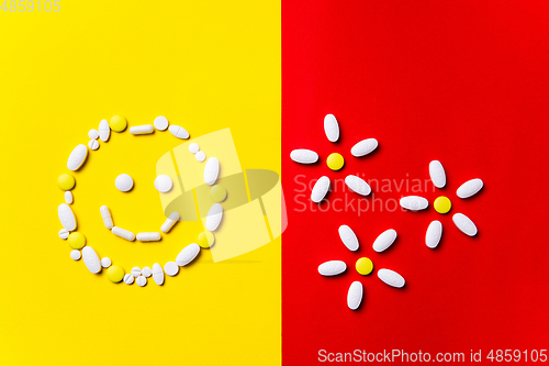 Image of Colored pills, tablets and capsules on a red and yellow background - history of treatment, prevention of pandemic