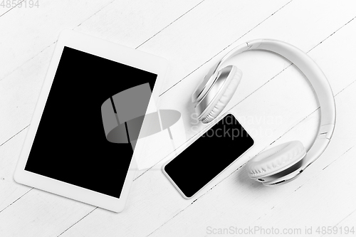 Image of Tablet and headphones. Monochrome stylish composition in white color. Top view, flat lay.