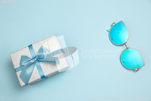 Image of Gift, present box and eyeglasses. Monochrome stylish composition in blue color. Top view, flat lay.