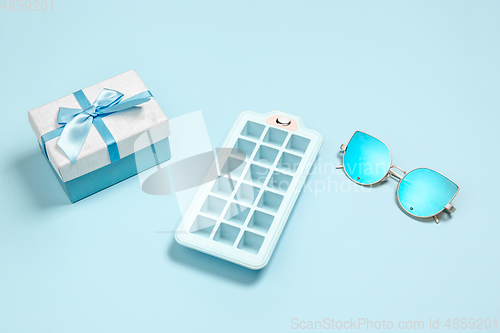 Image of Gift, present box, ice form and eyeglasses. Monochrome stylish composition in blue color. Top view, flat lay.