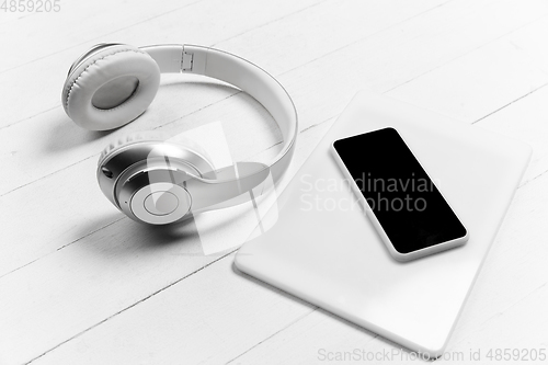 Image of Smartphone and headphones. Monochrome stylish composition in white color. Top view, flat lay.