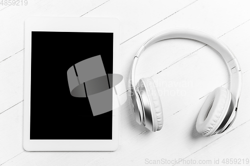 Image of Tablet and headphones. Monochrome stylish composition in white color. Top view, flat lay.