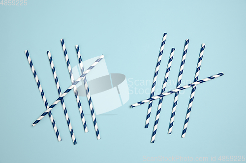 Image of Straws with strips. Monochrome stylish composition in blue color. Top view, flat lay.