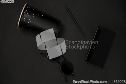 Image of Gadget, coffee and eyewear. Monochrome stylish composition in black color. Top view, flat lay.