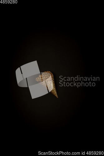 Image of Golden icecream waffle on a black background, stylish minimalistic composition with copyspace