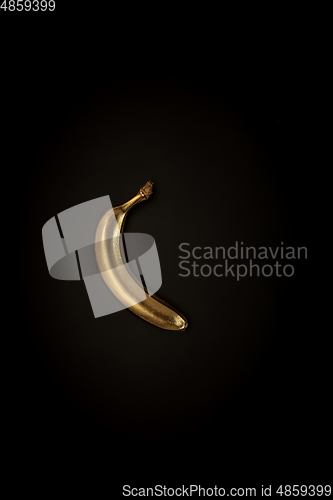 Image of Golden banana on a black background, stylish minimalistic composition with copyspace
