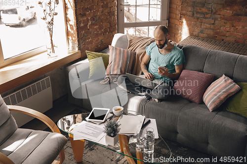 Image of Young man doing yoga at home while being quarantine and freelance working